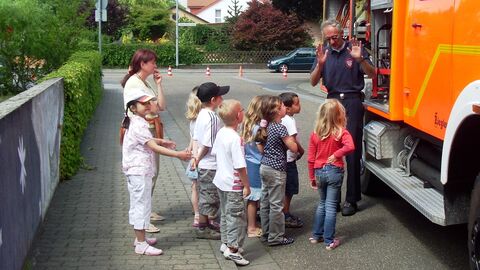 Brandschutzerziehung am Feuerwehrauto Kinder vor einem Feuerwehrauto
