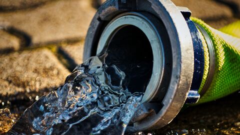 Feuerwehrschlauch mit auslaufendem Wasser